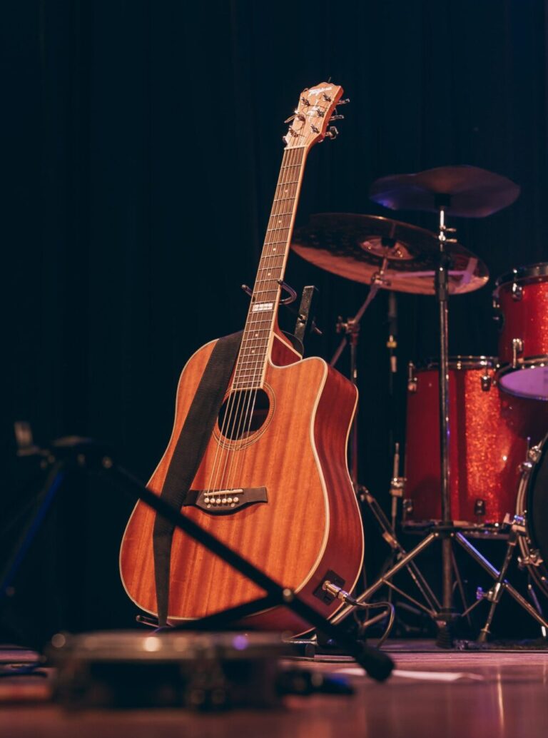 Eine Gitarre steht im Gitarrenständer auf einer Bühne